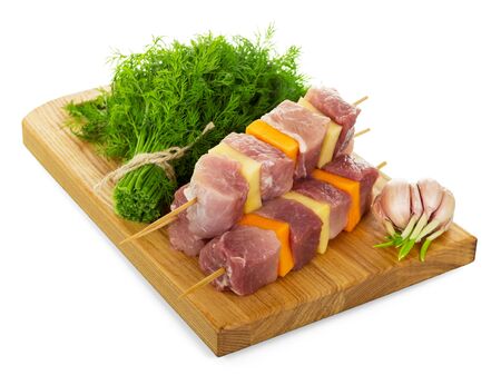 Skewers with slices of fresh pork, vegetables, dill, garlic and board isolated on white background.の写真素材