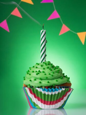 Cream cupcake decorated with a candle on a festive background with gifts. Birthday conceptの写真素材