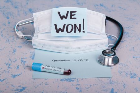 The concept of a stethoscope, a medical mask and a test tube with blood and the inscription we won and the quarantine is over. Close up.の写真素材