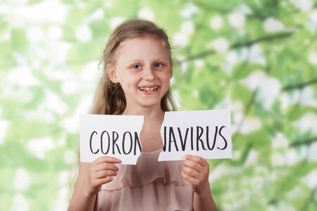 Happy little girl takes dergit torn inscription coronavirus outdoors. Victory over coronavirus. The...
