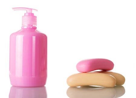 A bottle of pink liquid soap with a dispenser on one side of the bar of soap on the other. Close-up isolated on a white background.の写真素材