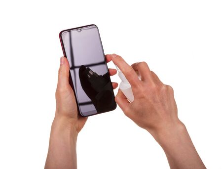 Female hands process the smartphone screen with sanitizreom. Shot close-up and isolated on a white background.の写真素材