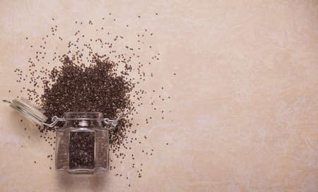 Glass storage jar with fresh healthy chia seeds on beige background. Top viewの写真素材