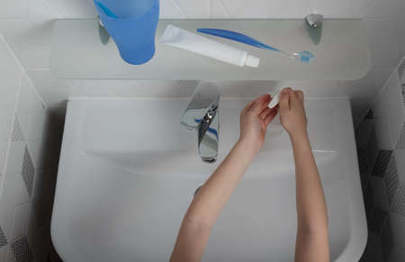 Bathroom. Baby hands pick up liquid soap for washing. Top view