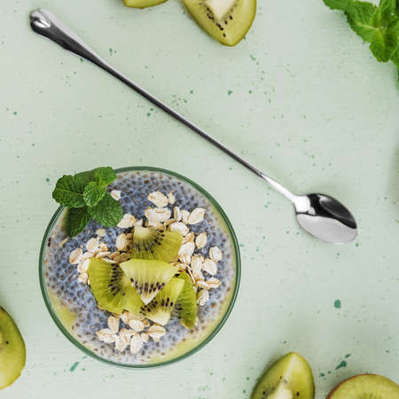 Healthy dessert, yogurt with chia seeds and fresh kiwi, mint leaves on a light backgroundの写真素材
