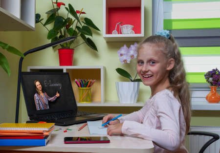 Distance learning concept. Happy girl runs the school program remotely using a laptop