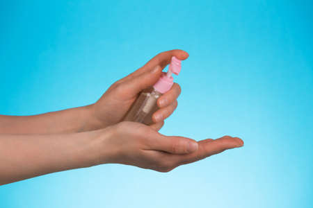 Pandemic covid-19. Hand treatment with antiseptic gel on a pink backgroundの写真素材