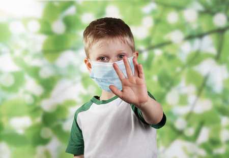 Showing stop gesture with palm. Boy in face mask points out need to keep distance during COVID-19 epidemicの写真素材