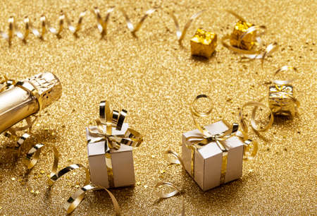 Happy new year and merry christmas. Bright gold card with champagne and gifts decorated with gold tinselの写真素材