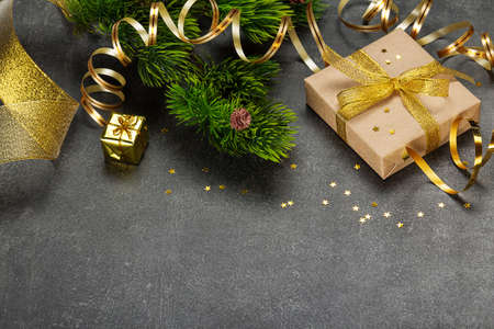 Branch of christmas tree decorated with a golden serpentine, gifts with a beautiful ribbon and...