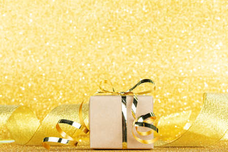 Gift close-up on gold ribbon background and sparkling bright backgroundの写真素材