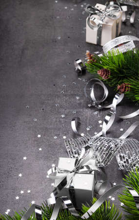 New Year concept. Bright christmas gift with silver ribbon close up, fir tree and stars confettiの写真素材