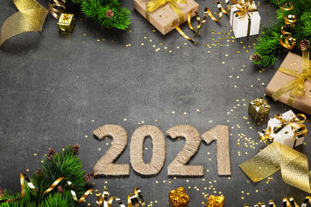 Top view. Happy new year 2021. Bright card with golden serpentine and ribbons, christmas gifts on dark backgroundの写真素材