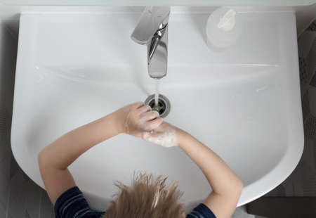 Top view. Little boy washes his hands with soap in the sink in the bathroomの写真素材