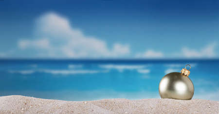 Christmas ball in the sand on the beach on a bright sunny day of new years eveの写真素材