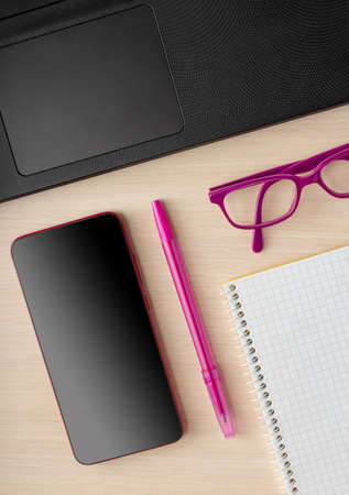 Remote work concept. Laptop, phone, notebook for notes and glasses on the table. Top viewの写真素材
