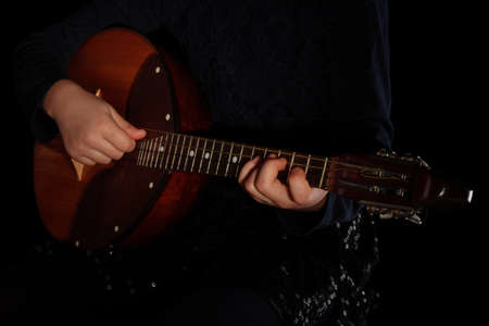 Childrens hands playing domra musical instrument isolated on black backgroundの写真素材