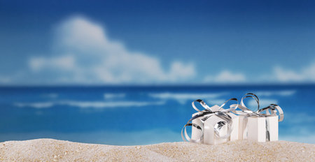 Gifts with silver ribbon in the sand on beach on a sunny dayの写真素材