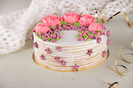 Delicious round cake decorated with cream flowers on a table with a napkinの写真素材