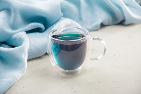 Blue tea in a transparent cup with a double bottom on a light background and a napkinの写真素材