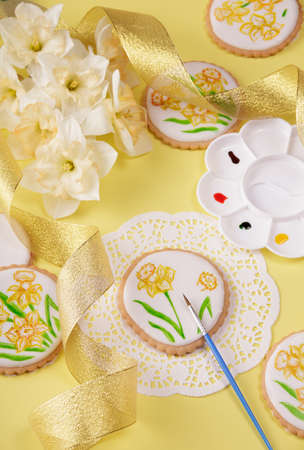 Spring mood. Top view. The pastry chef paints the gingerbread with a brush. Daffodil bouquetの写真素材