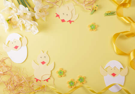 Festive composition for Easter. Chickens made of paper, golden ribbon and easter decor on yellow backgroundの写真素材