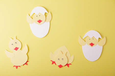 Top view. Origami. Chickens made of colored paper on a yellow backgroundの写真素材