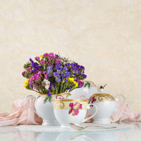 Good morning concept. Tea in beautiful cups and a teapot on a light background with dried flowersの写真素材