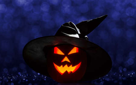 Favorite Halloween holiday. Pumpkin Jack a burning lantern with a creepy grin in a cap on a dark backgroundの写真素材