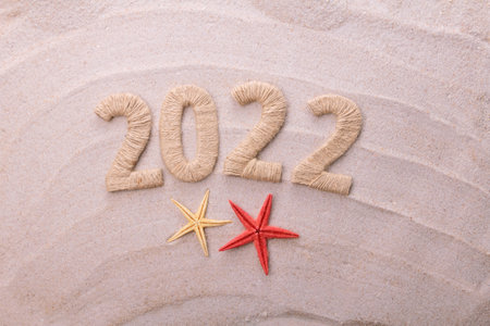 Top view. Inscription 2022 made of twine on a background of sea sandの写真素材