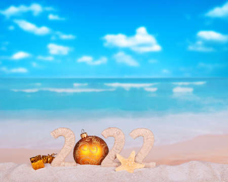 New Year's on a sunny beach. The inscription 2022 in the sand against the background of the seaの写真素材