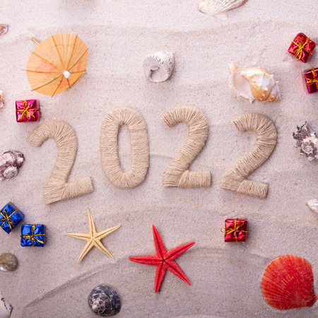 Top view. New year 2022 and sandy beach. Starfish and seashells with Christmas giftsの写真素材