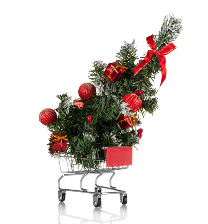 Christmas shopping. Christmas tree with new year balls in a shopping cart isolated on white backgroundの写真素材