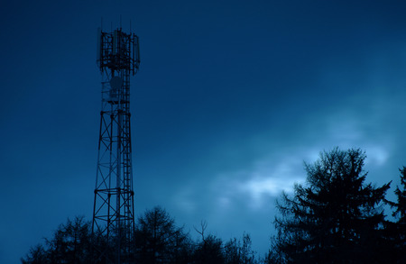 Blue sky with silhouette of transmitter and tree