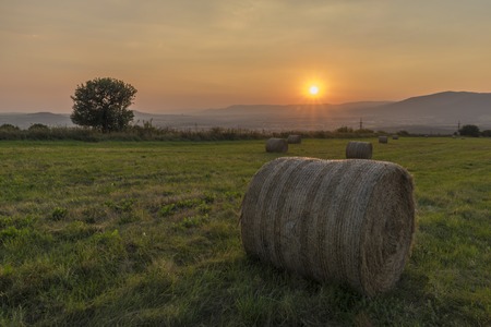 Hay balls with sunset over Krusne hory mountains