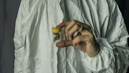 Medical marijuana in transparent and yellow plastic box in handsの写真素材
