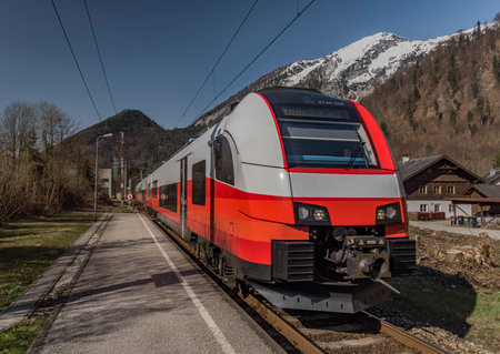 Red electric fast train in Austria Alps mountains in sunny spring dayの写真素材