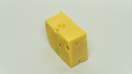 Yellow not fresh cheese with big holes and white backgroundの写真素材