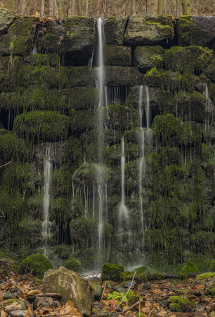 Cascade with waterfalls on Prucelsky creek in Ceske Stredohori mountains in winter dark cloudy dayの写真素材