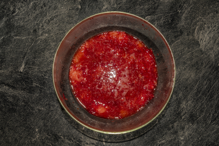 Making of young strawberries with sugar on black table in white tile kitchenの写真素材
