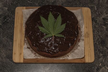 Making of marijuana brown cake with peach and strawberry fruit and cannabis green leafの写真素材