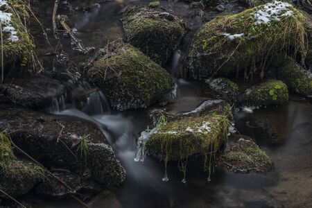 Hodslavsky creek with snow and ice in snowy winter day in Sumava national park in south Bohemiaの写真素材