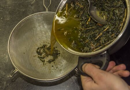 Making of marijuana butter on cooker in kitchen with leafs and yellow butter which will be green