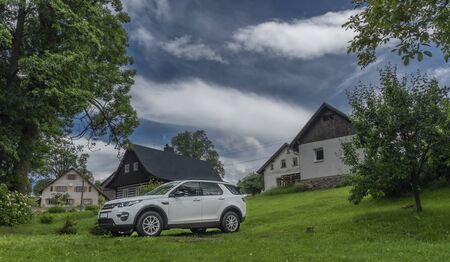 White big offroad car in counry village on green meadow in blue sky clouds dayの写真素材