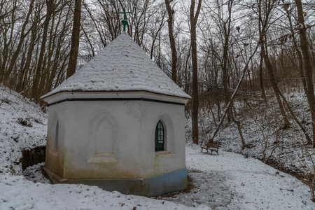 Whtie chapel with green crucifix near waterfall Moravsky Krumlov in winter cold snowy morningの写真素材