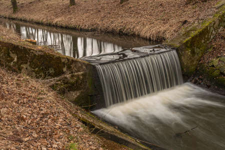 Dobrovodsky creek with cascade and concrete pipe in cold winter dark dayの写真素材