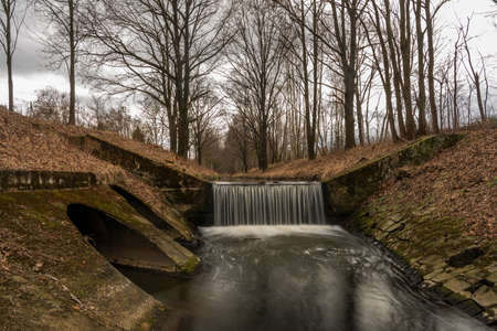Dobrovodsky creek with cascade and concrete pipe in cold winter dark dayの写真素材