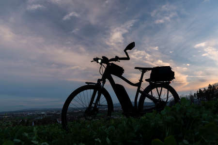 Black and gray electric bicycle in sunset time with cloudy sky over Ceske Budejovice cityの写真素材