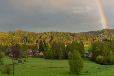 Rainbow over Bernov village in sunset evening with green fresh meadowsの写真素材