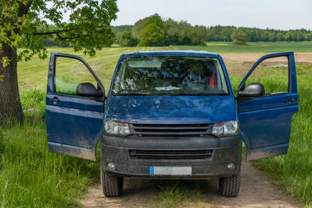 Blue big van on path in green spring fresh nature